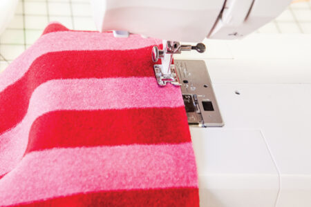 pink and red fabric being sewn on a sewing machine